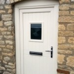 Secure composite front door by Apeer, installed by Cliffside Windows in Lincolnshire. Cream front door in a stone wall with glazed window.